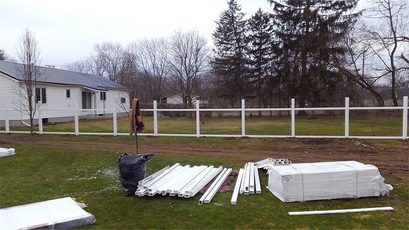 A white fence is being built in the backyard of a house
