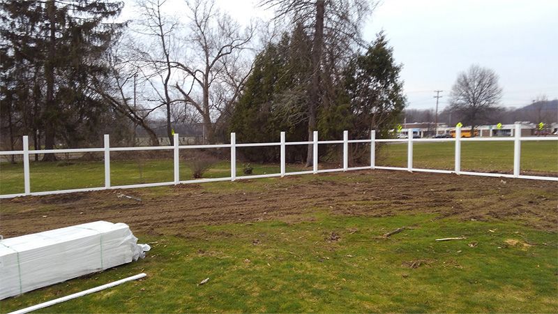 A white fence is sitting in the middle of a grassy field.