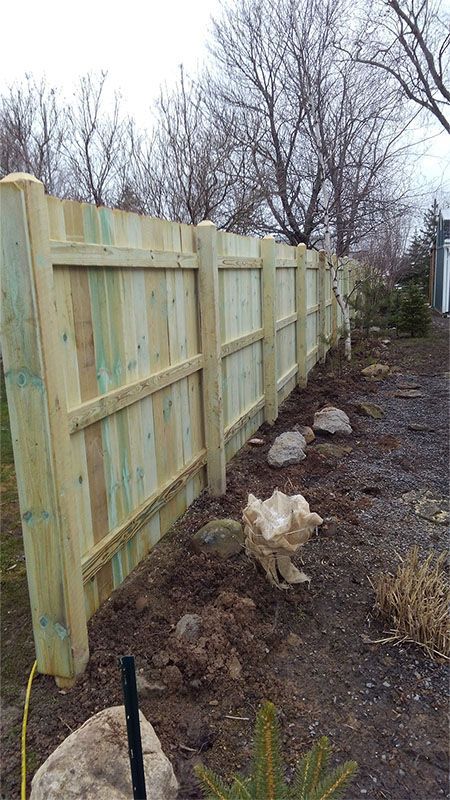 A wooden fence is sitting in the middle of a dirt field.