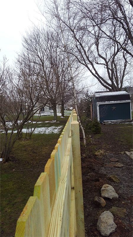 A wooden fence is being built in the backyard of a house.