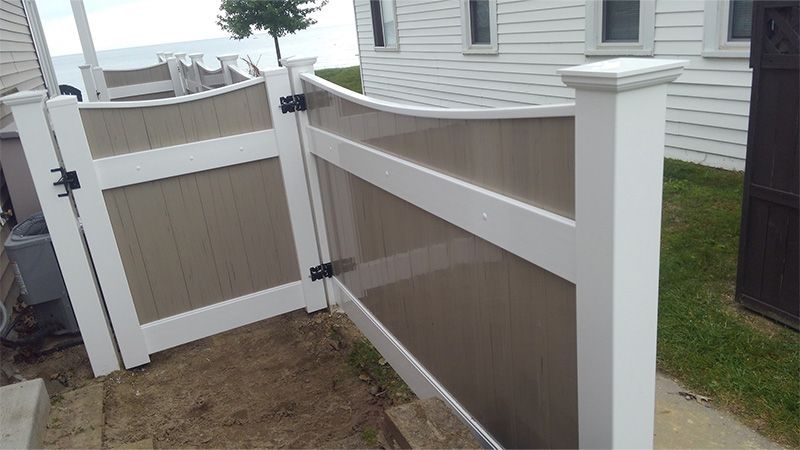 A white fence with a gate in front of a house.