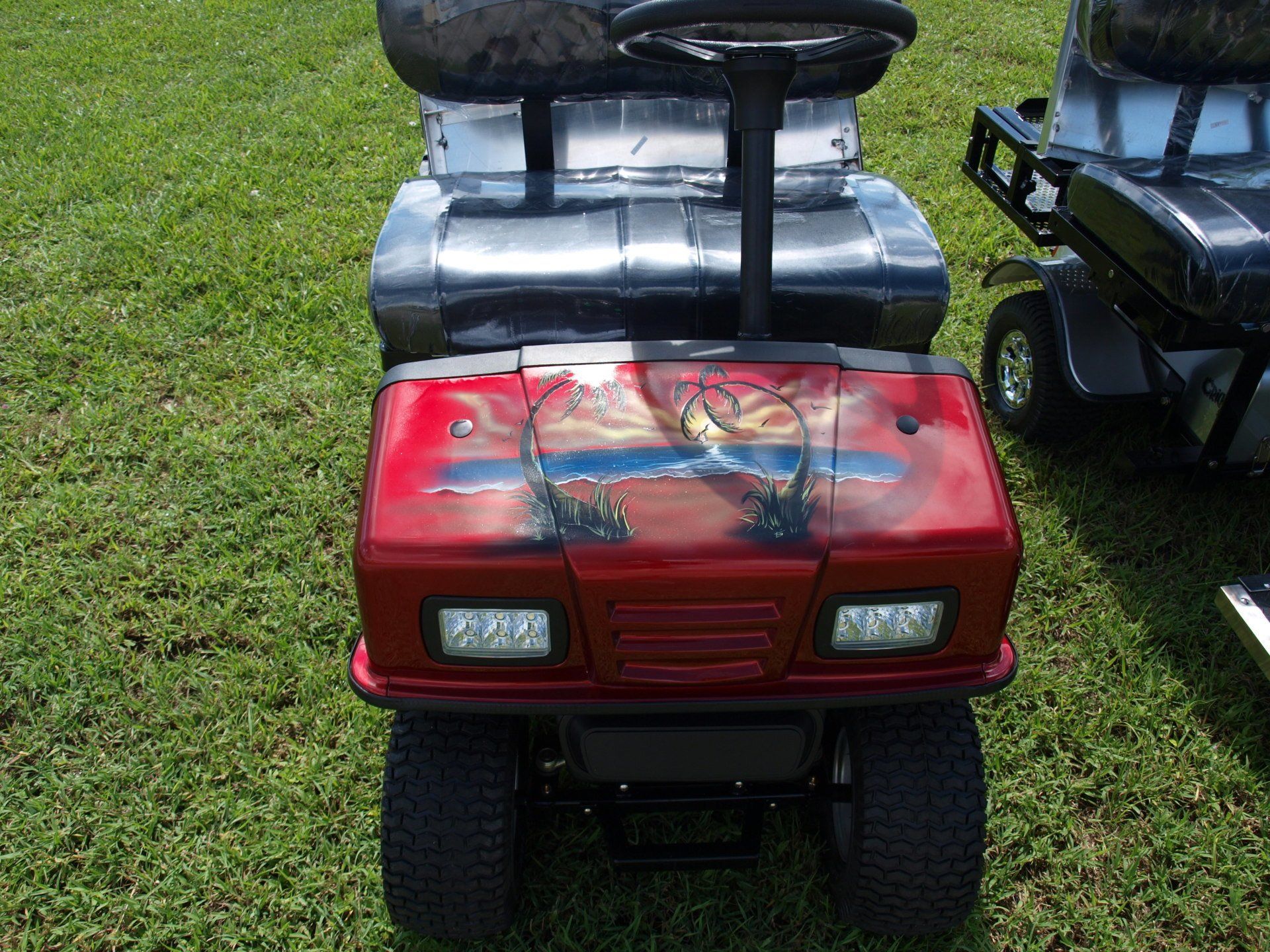A red golf cart is parked in the grass