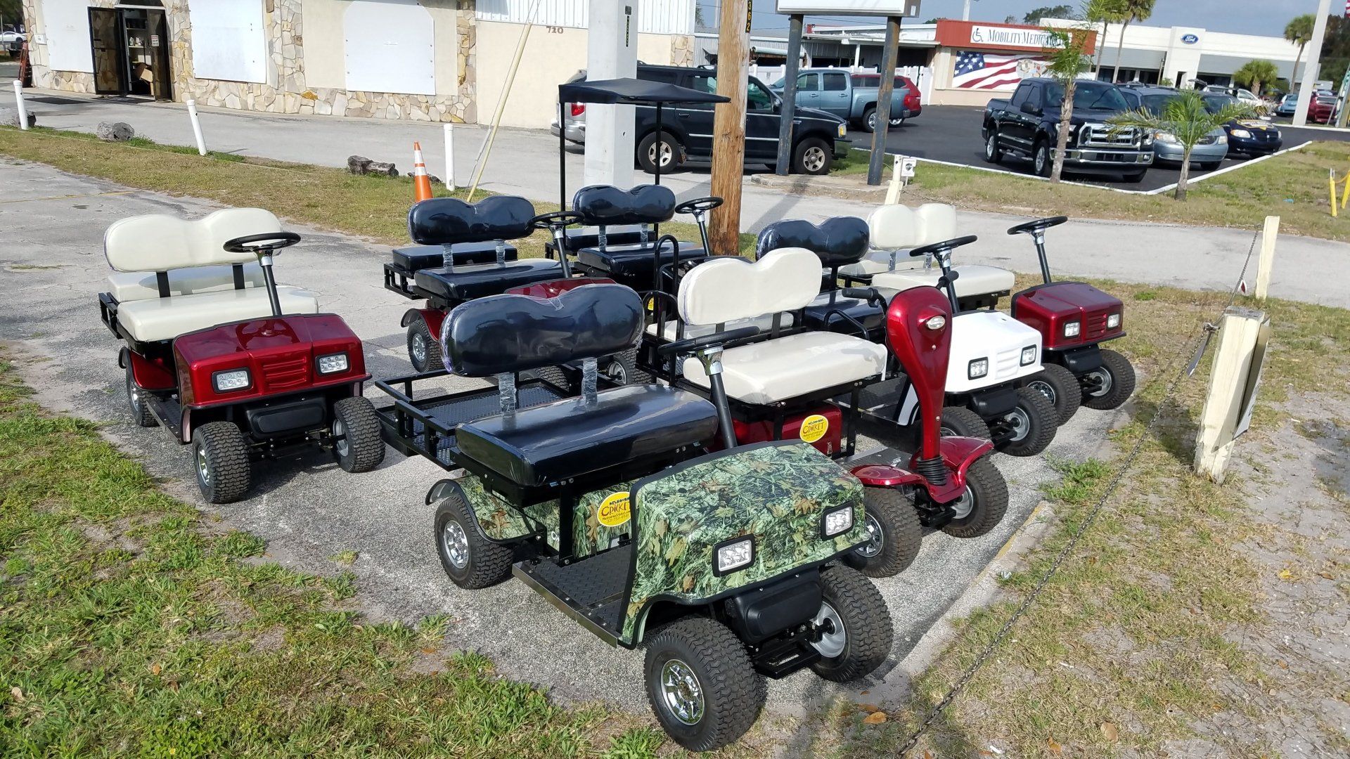 A bunch of golf carts are parked on the side of the road.