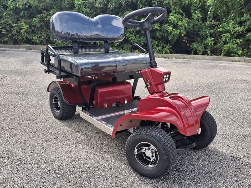 Three golf carts are parked in the grass near a body of water