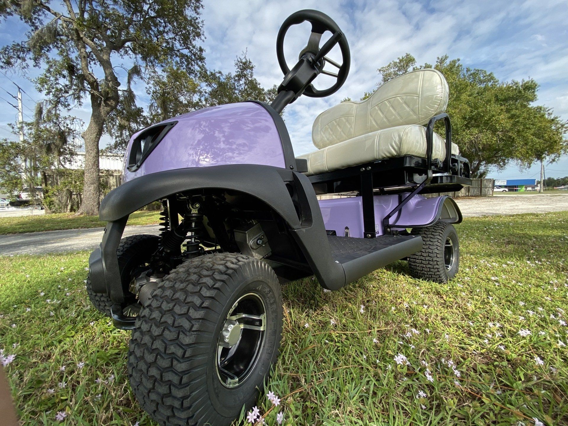 A purple golf cart is parked in the grass.