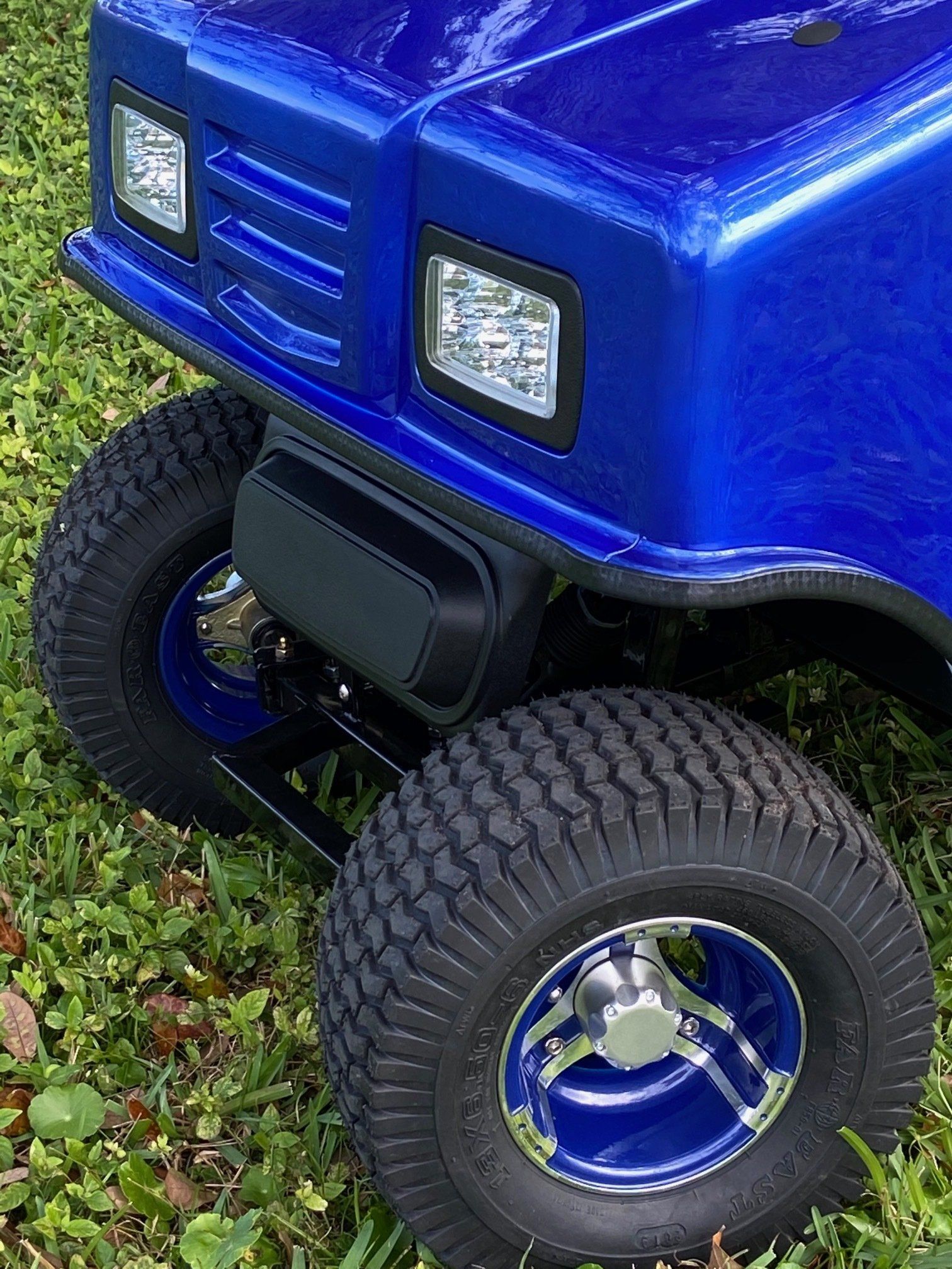 A blue golf cart is parked in the grass.