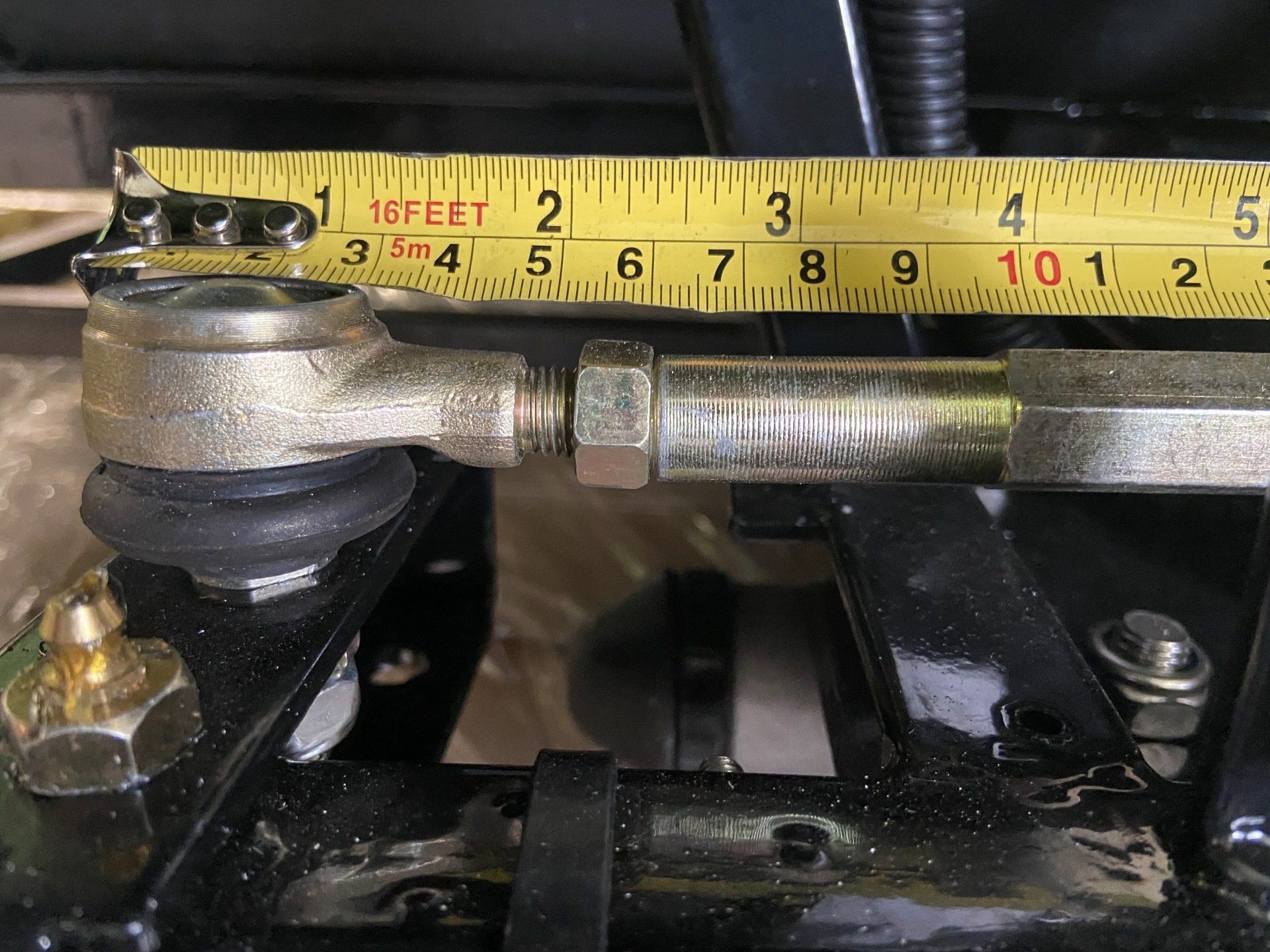 A yellow measuring tape is being used to measure a metal object