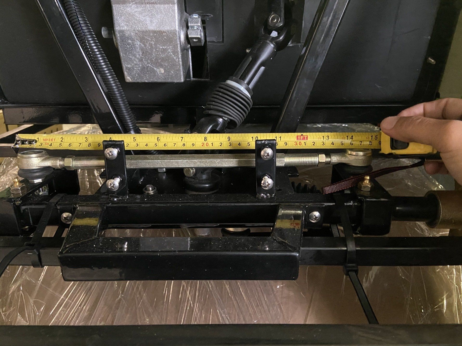 A person is measuring a piece of metal with a tape measure.