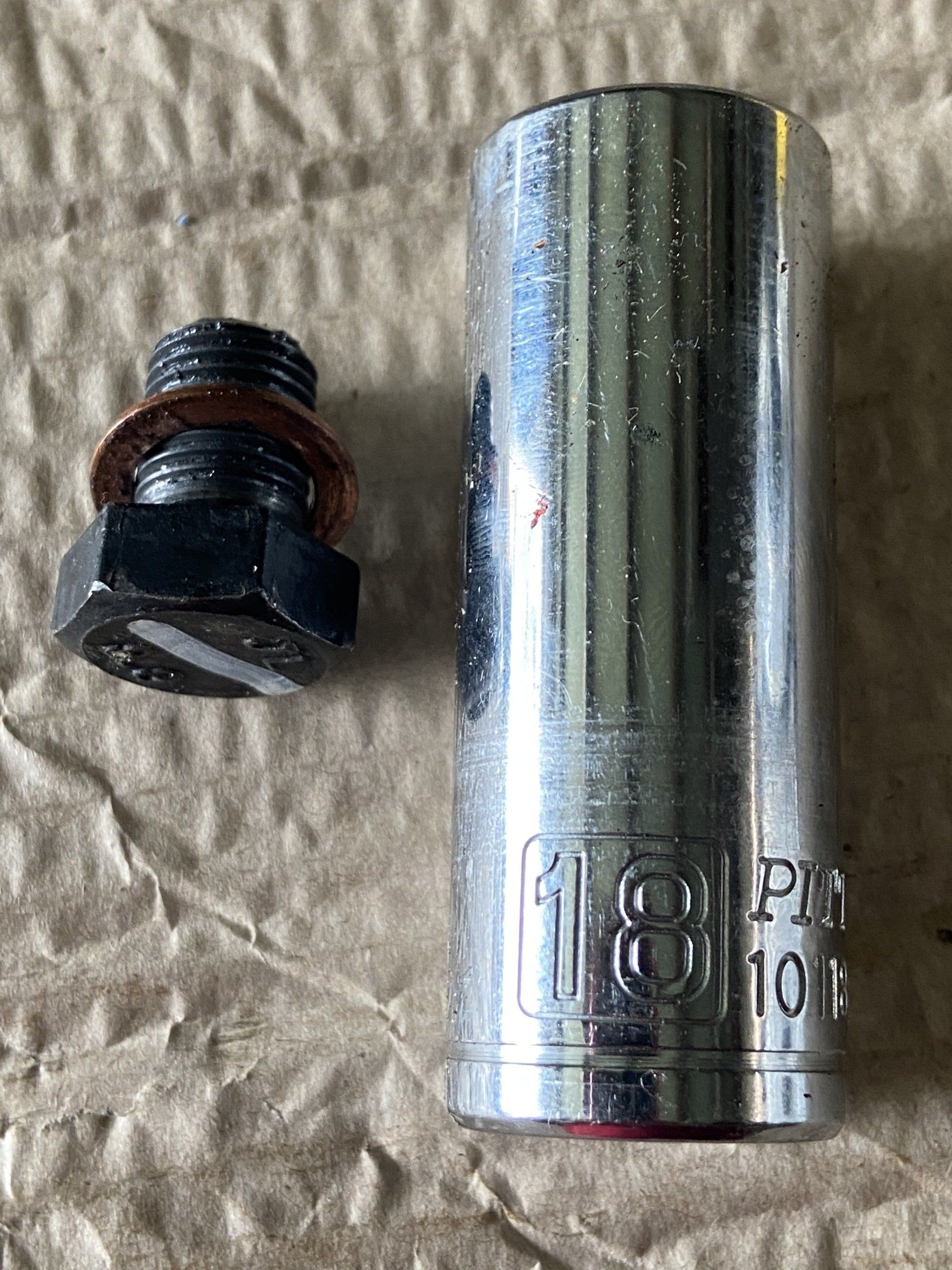 A socket wrench and a plug are sitting on a piece of cardboard.