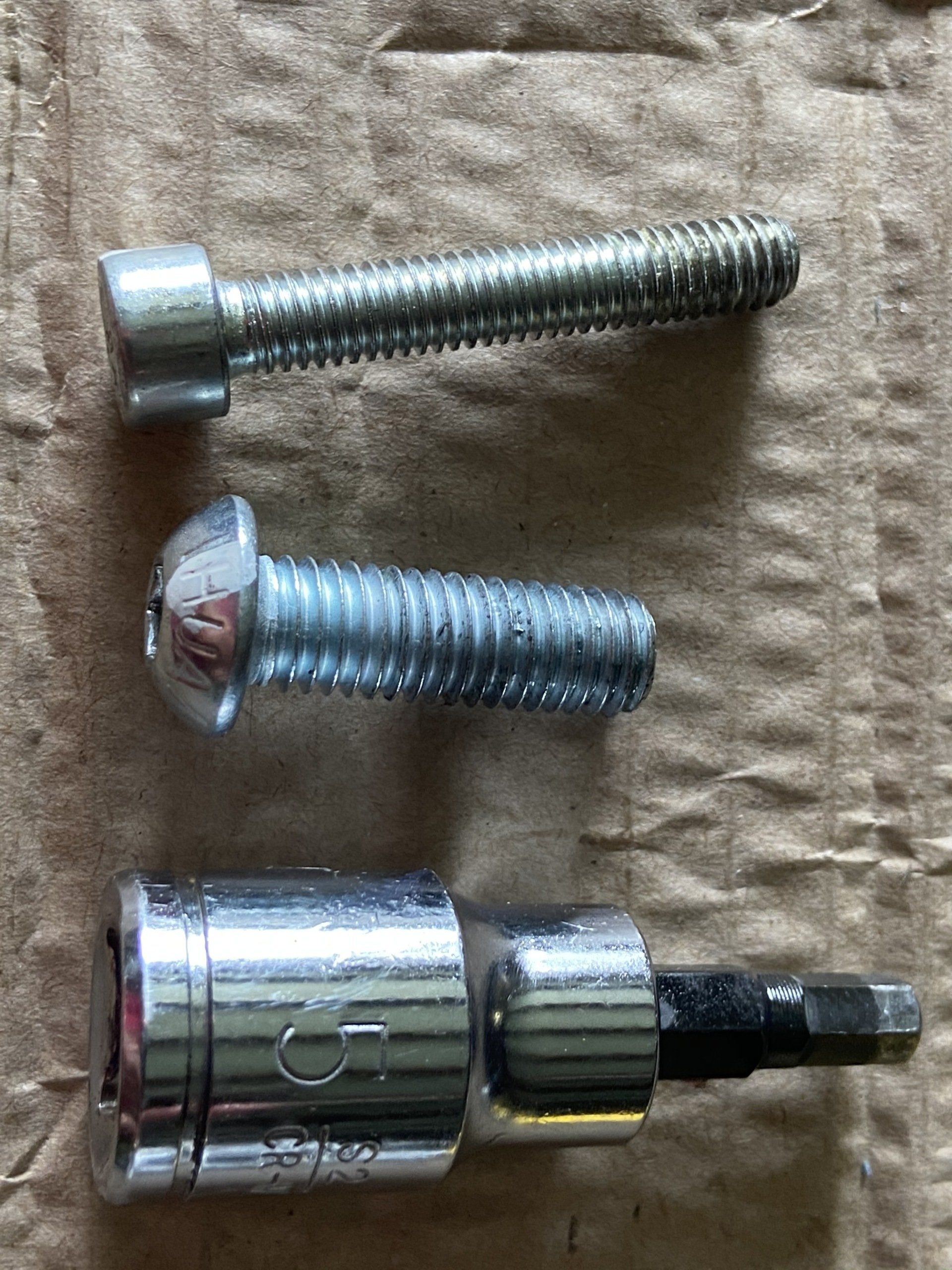 A close up of three screws and a socket on a piece of cardboard.