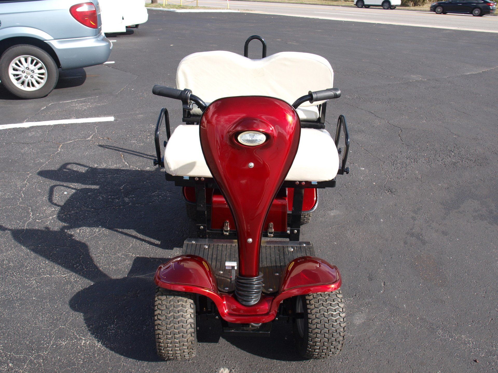 A red golf cart is parked in a parking lot