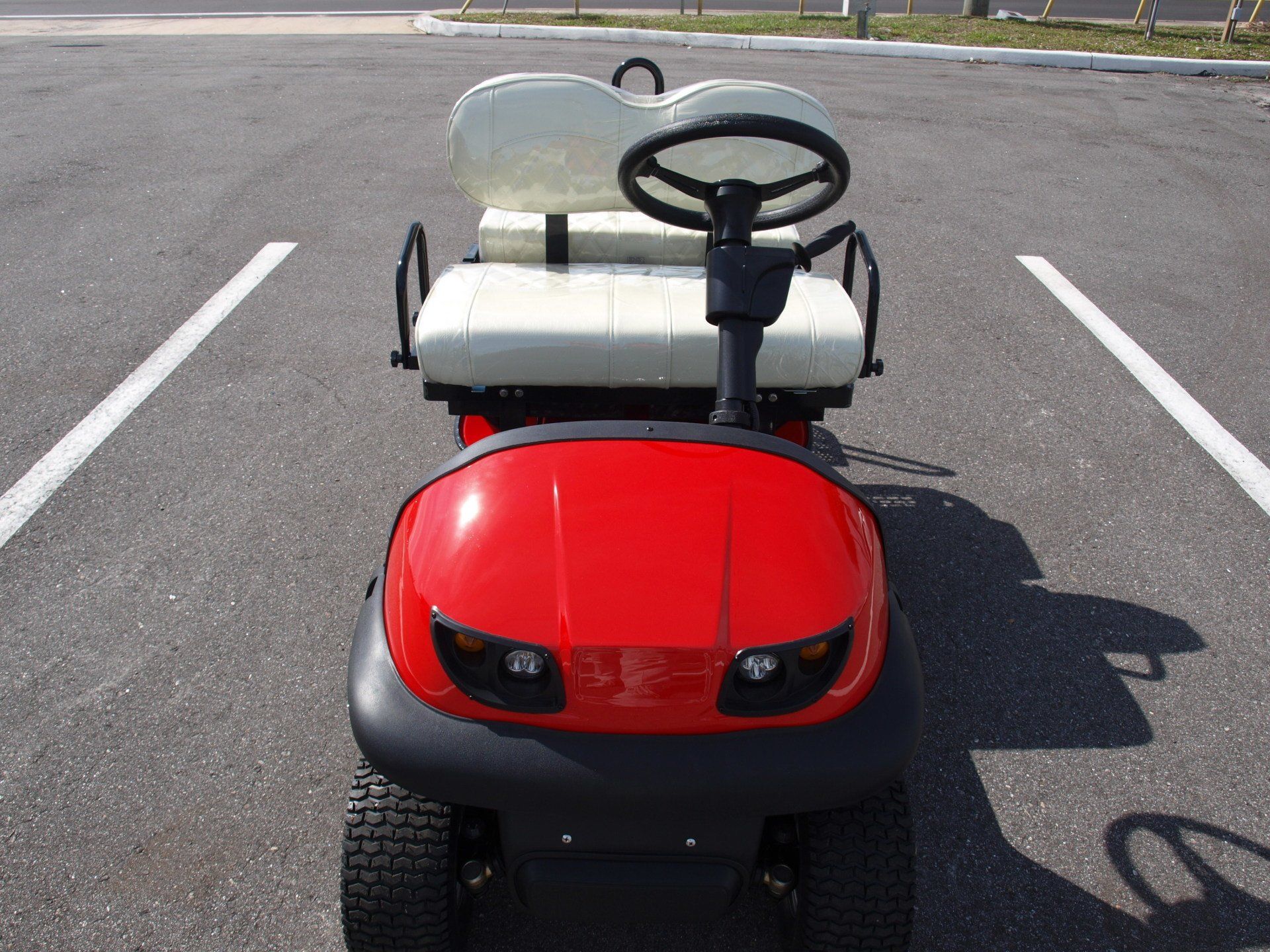 A red golf cart is parked in a parking lot