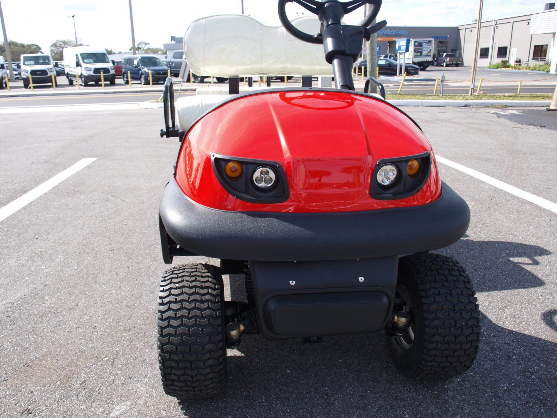 A red golf cart is parked in a parking lot