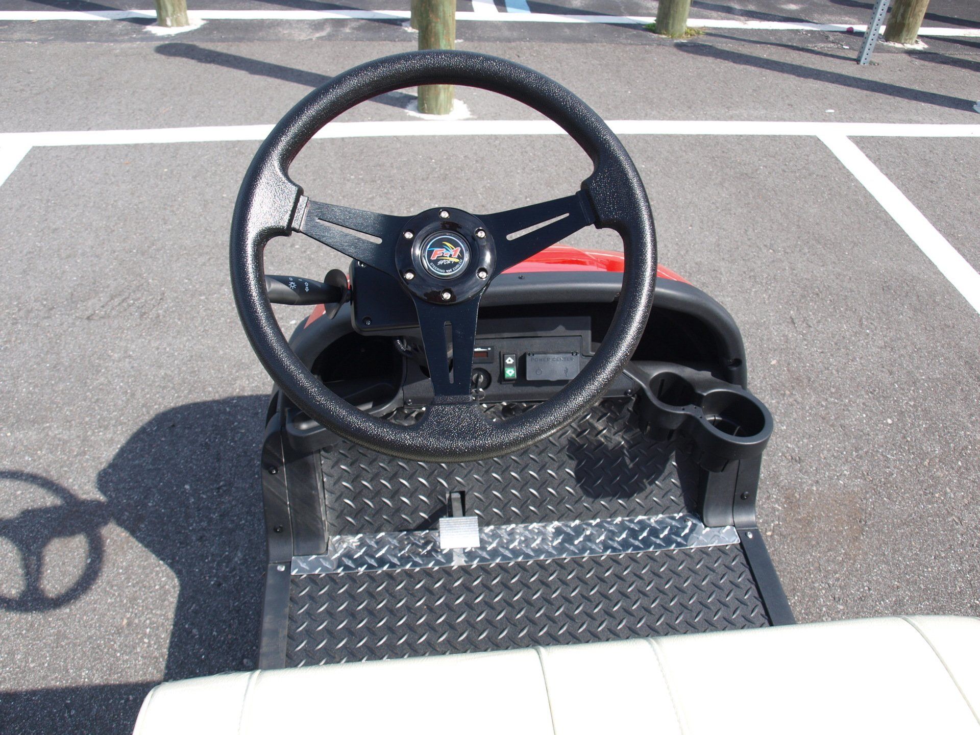 A golf cart with a steering wheel in a parking lot