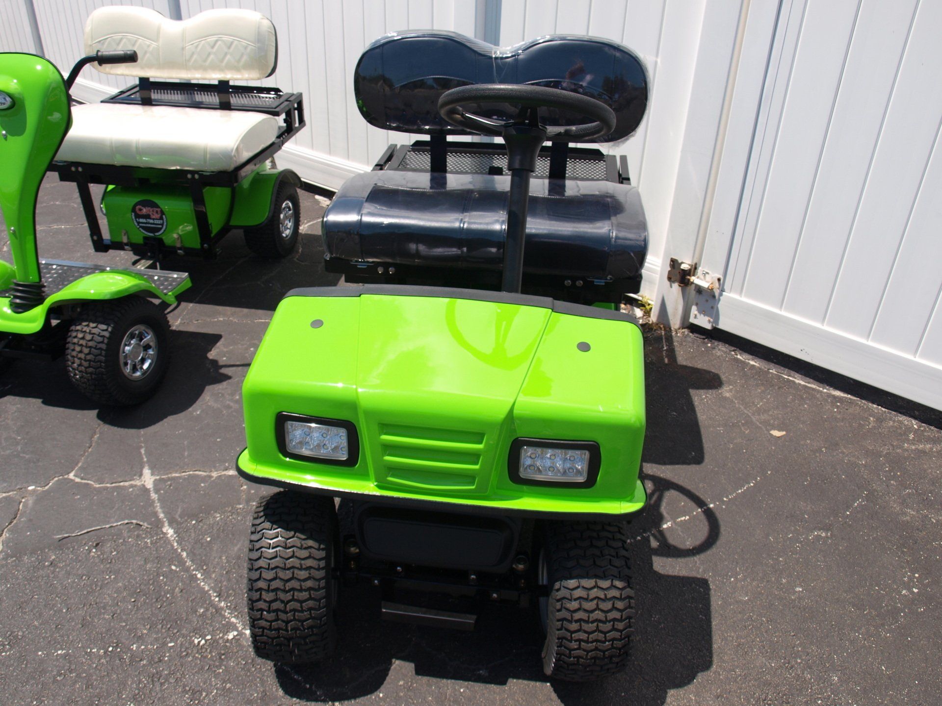 A green golf cart is parked next to a white fence