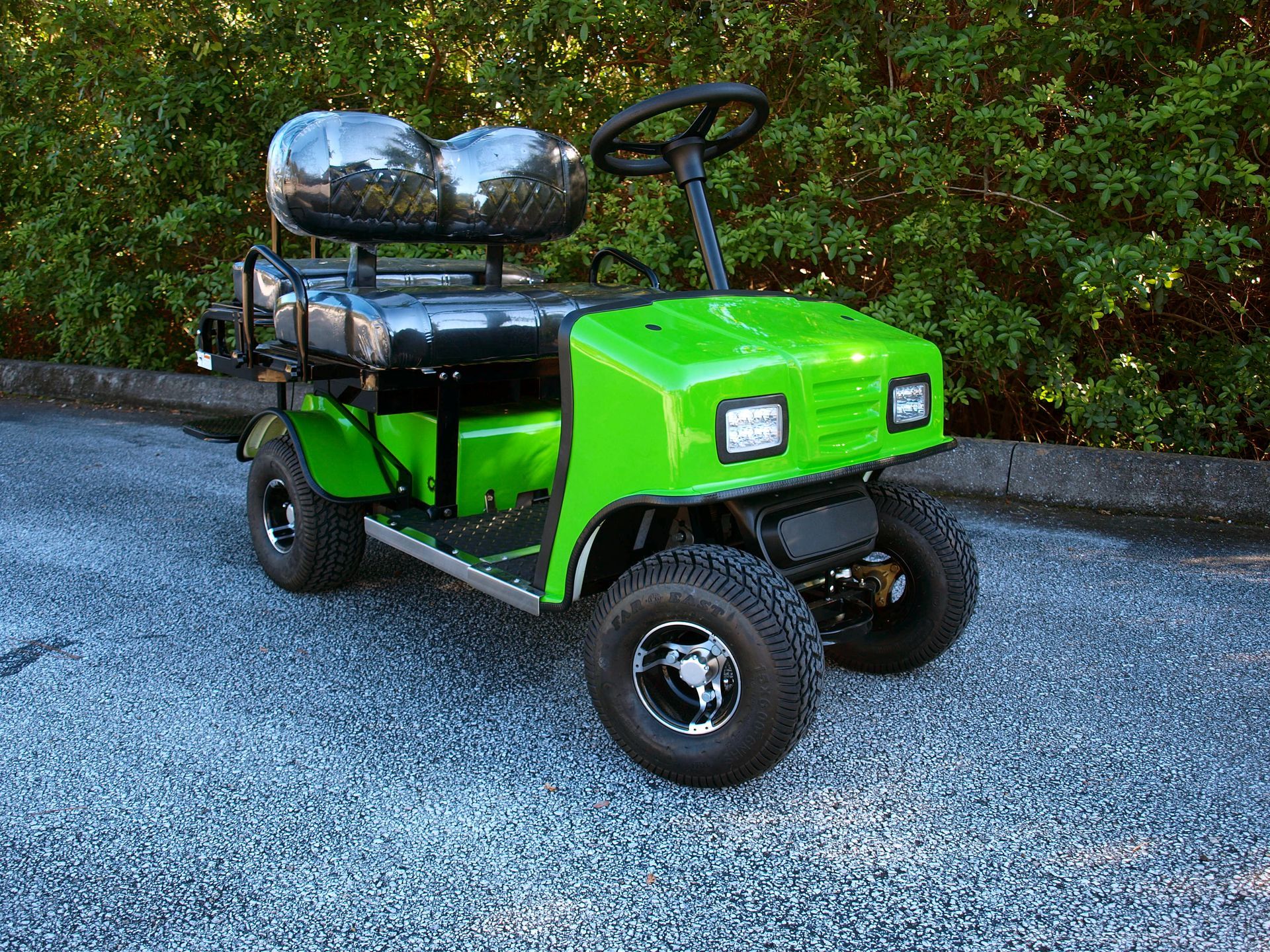 A green golf cart is parked on the side of the road.