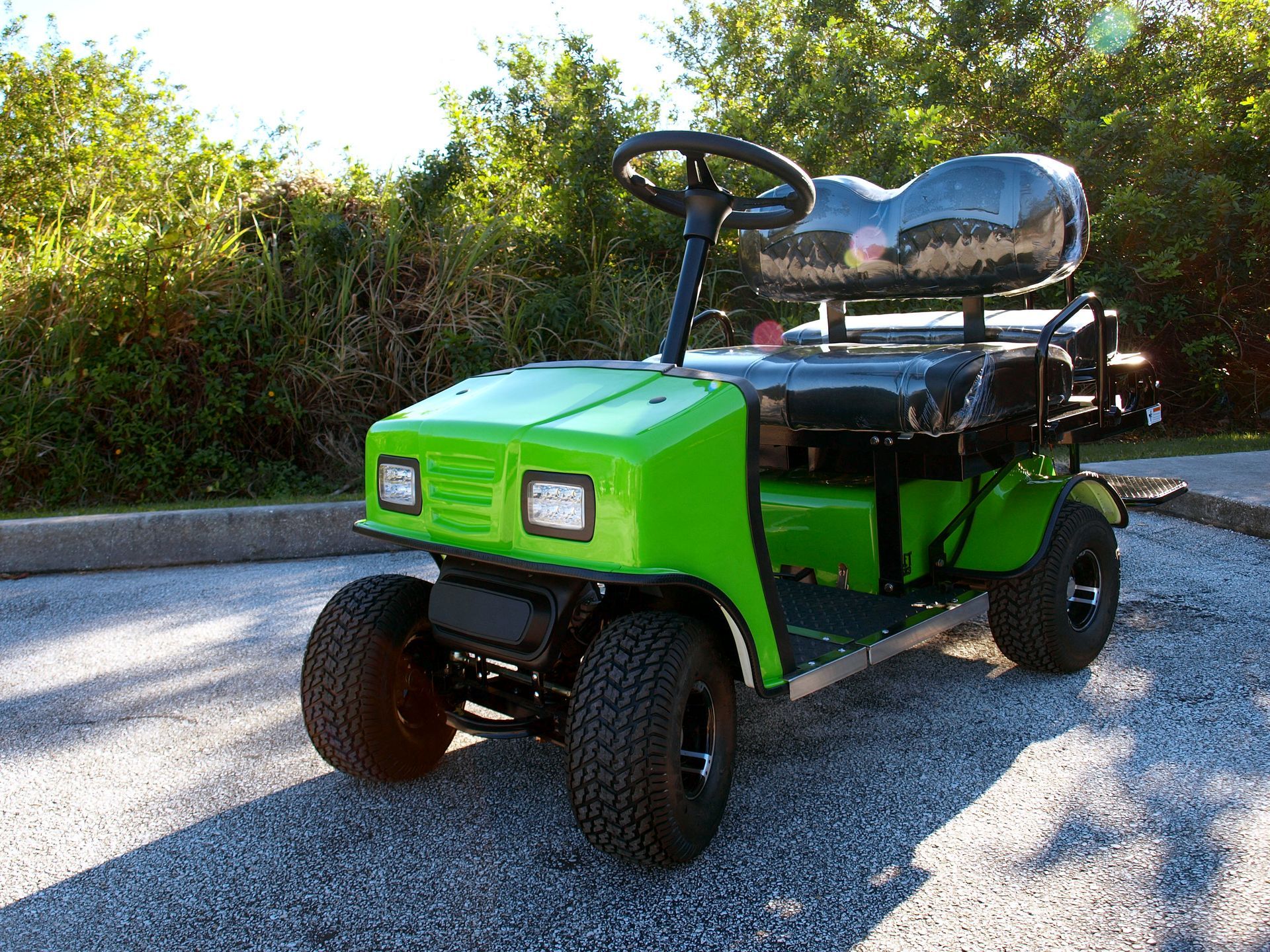A green golf cart is parked on the side of the road.