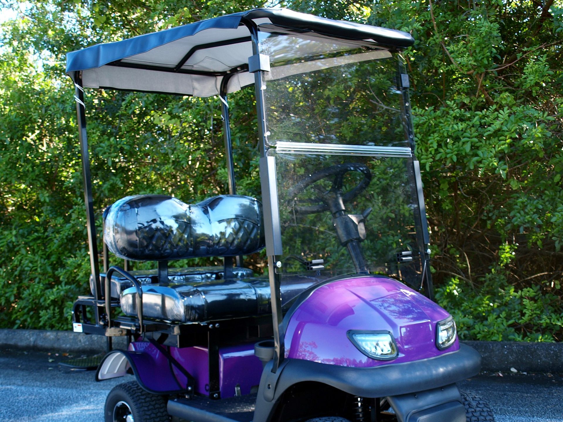 A purple golf cart is parked on the side of the road