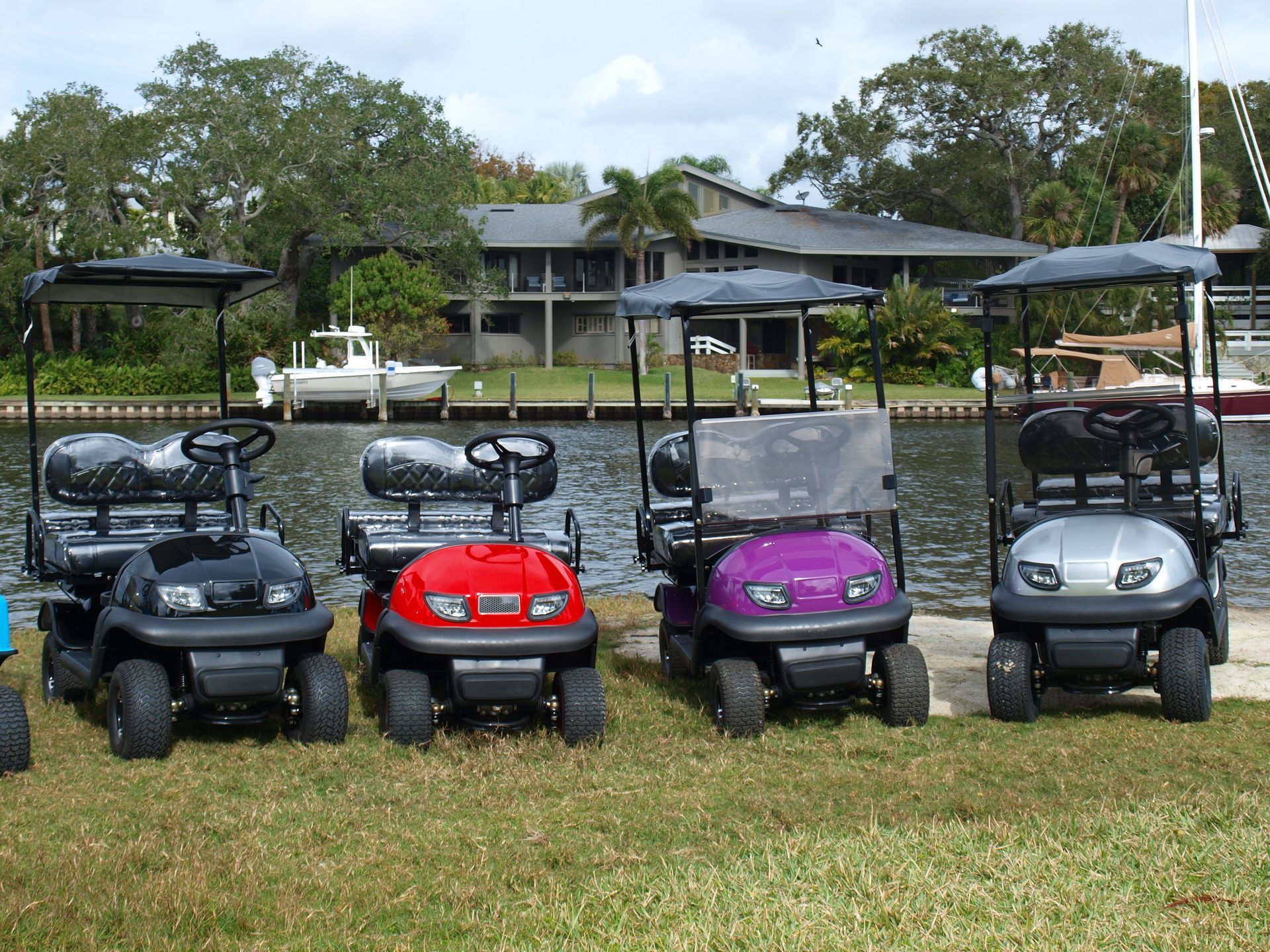 Four golf carts are parked next to each other in front of a body of water