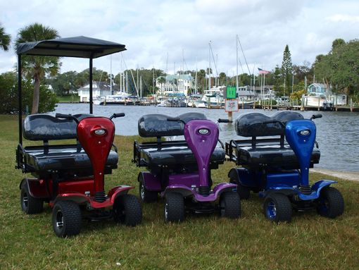 Three golf carts are parked in the grass near a body of water