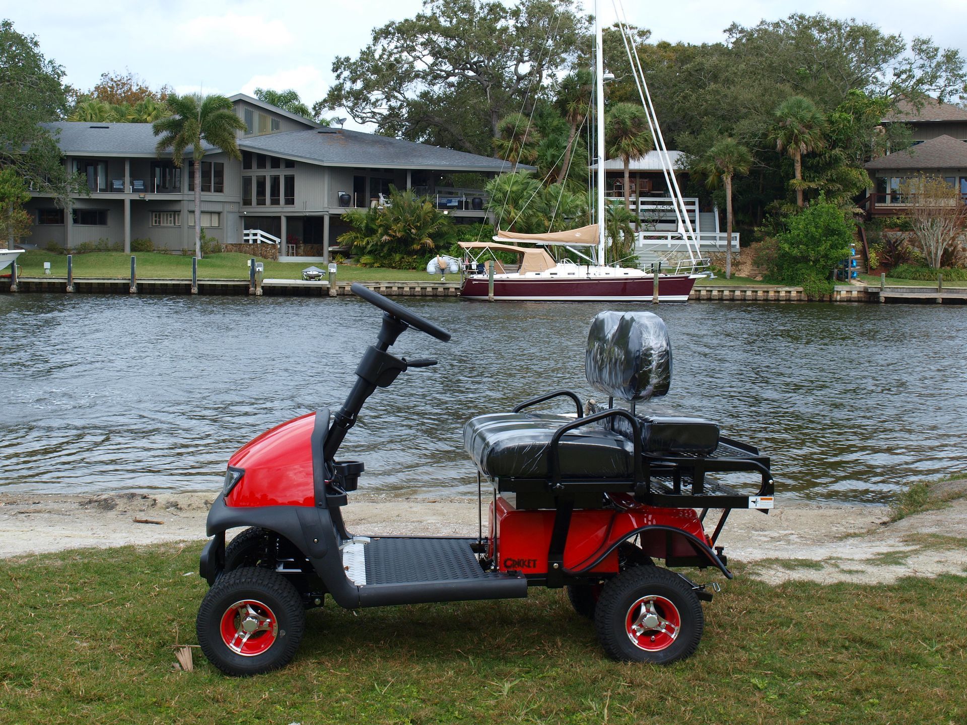 A red golf cart is parked next to a body of water
