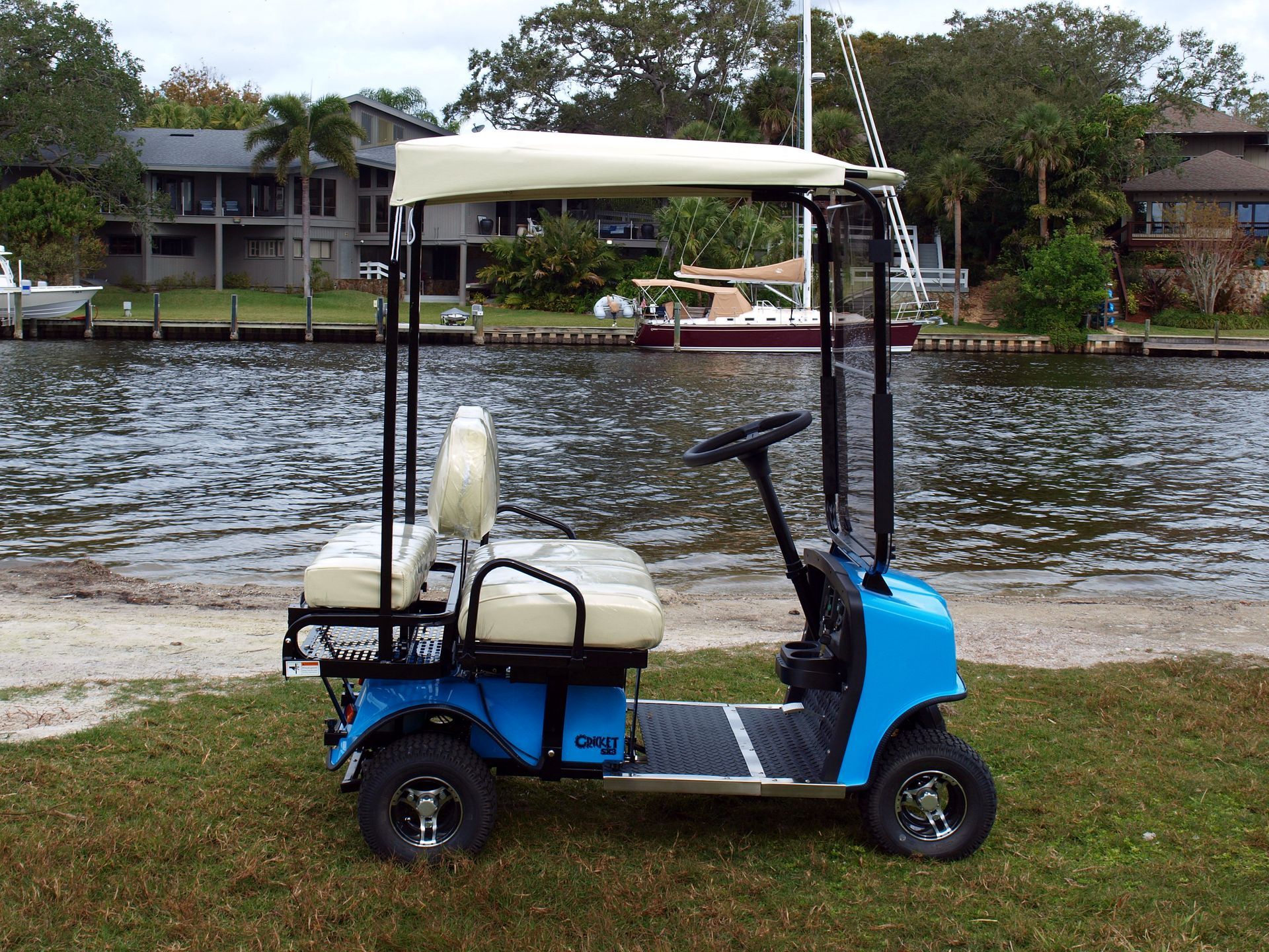 A blue golf cart is parked in front of a body of water