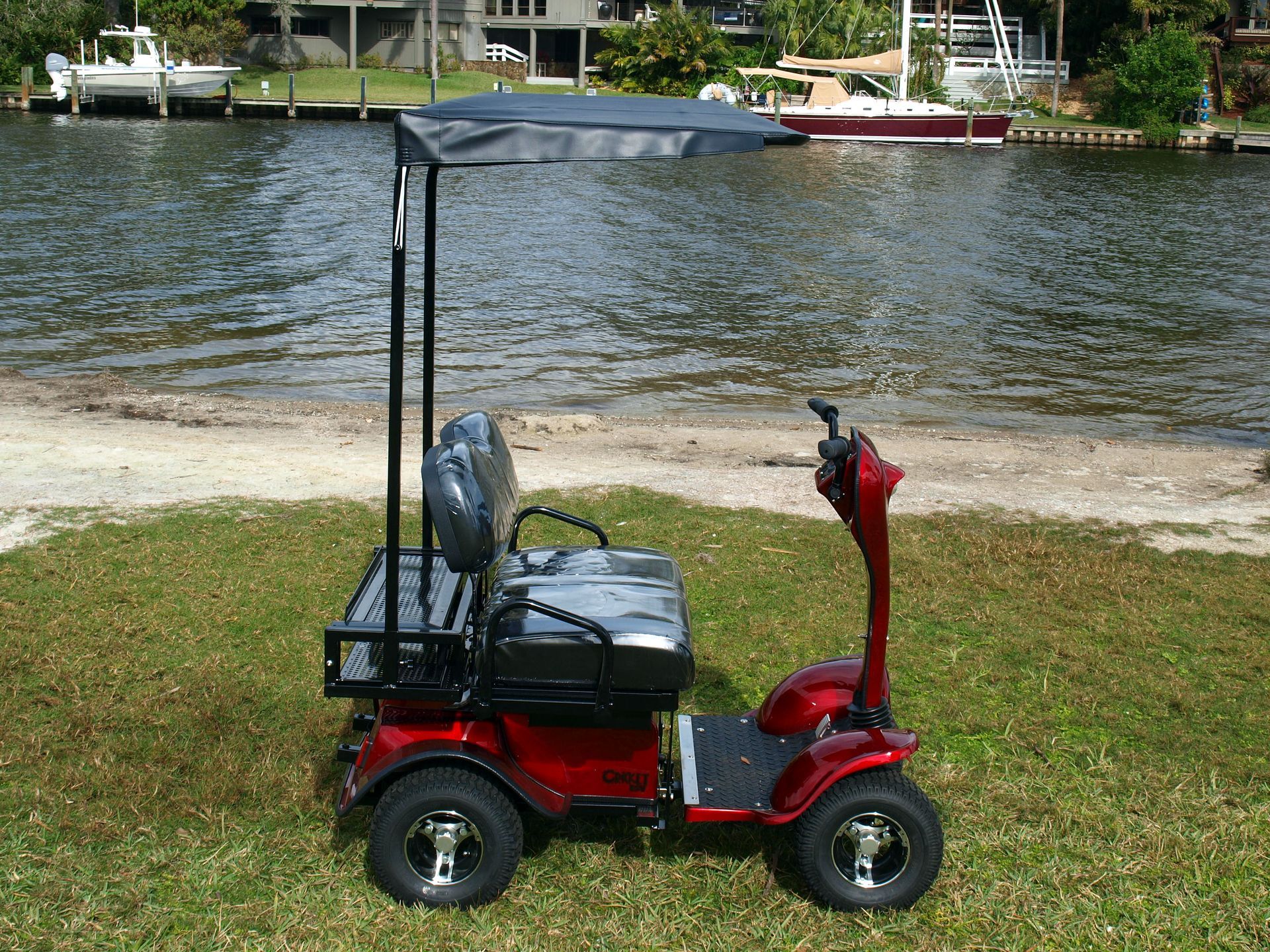 A red ESV with a canopy is parked in front of a body of water