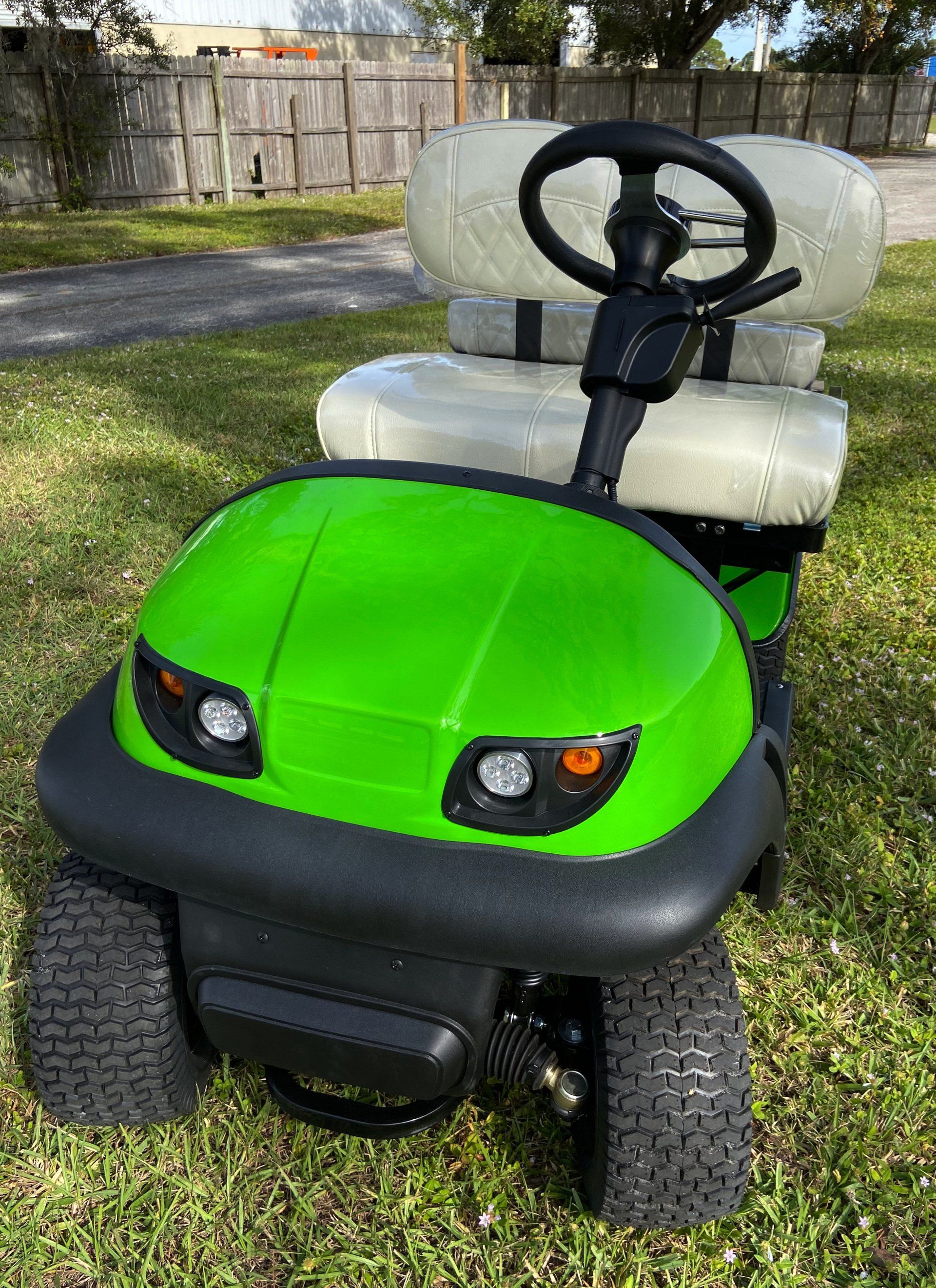 A green golf cart is parked in the grass.