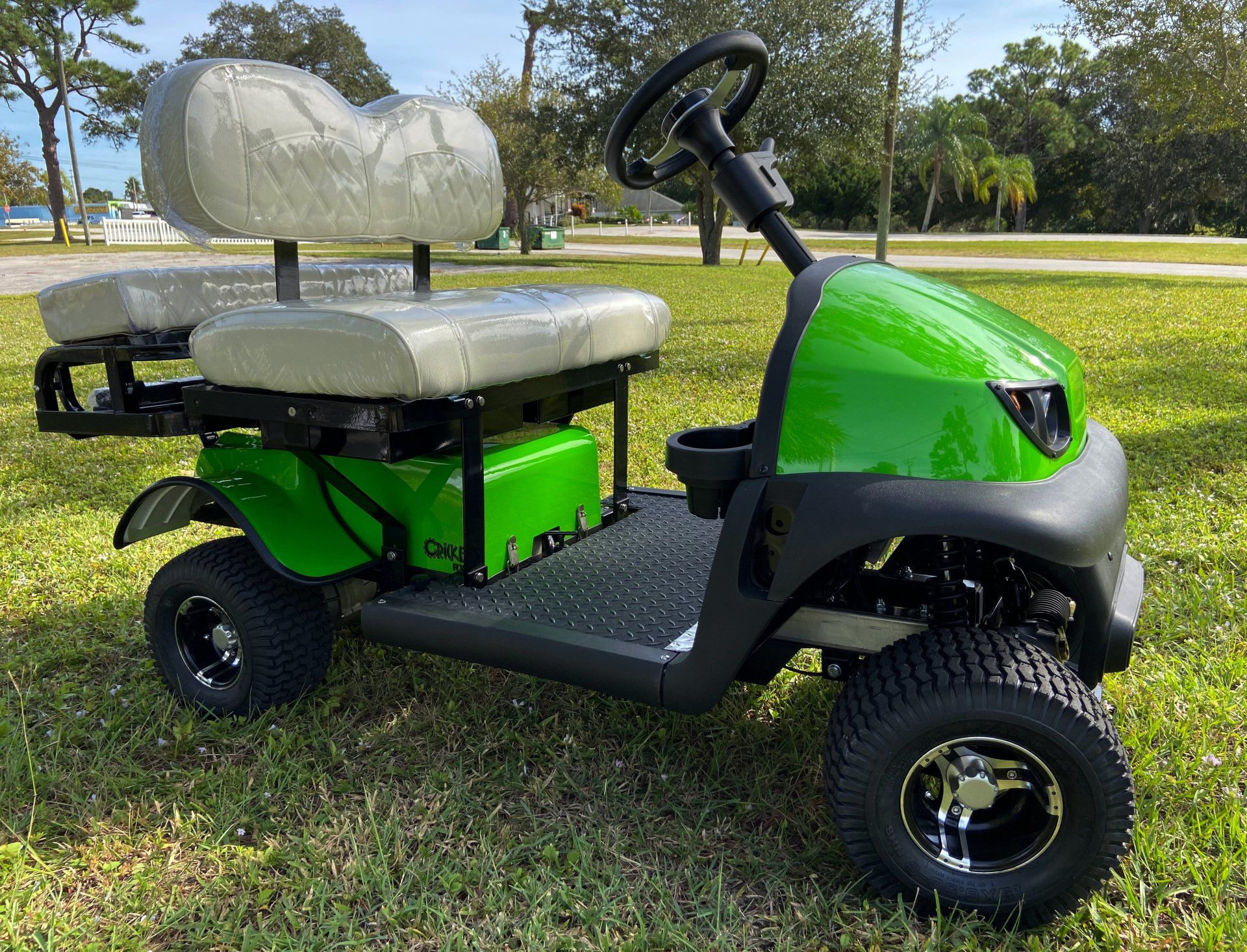 A green golf cart is parked in the grass.