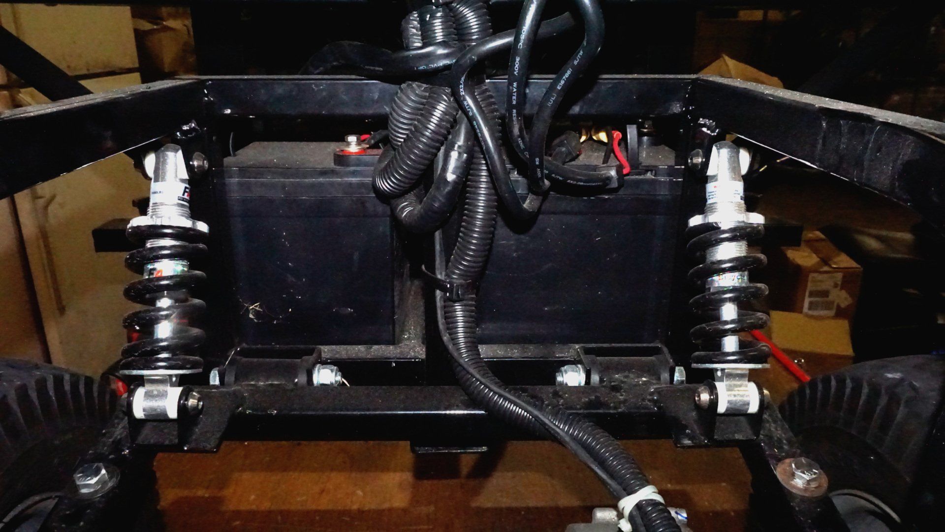 A black vehicle with a battery and shocks attached to it