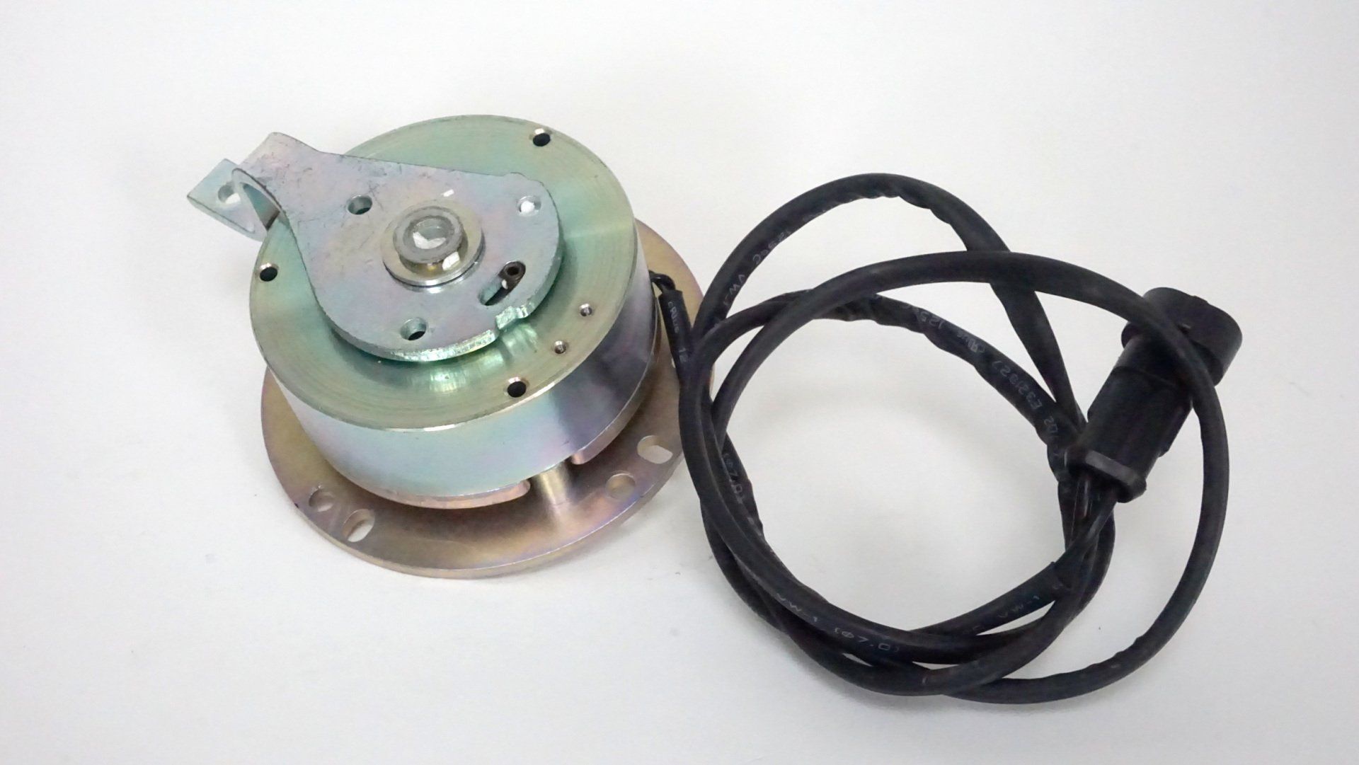 A motor with a cord attached to it is sitting on a white surface.