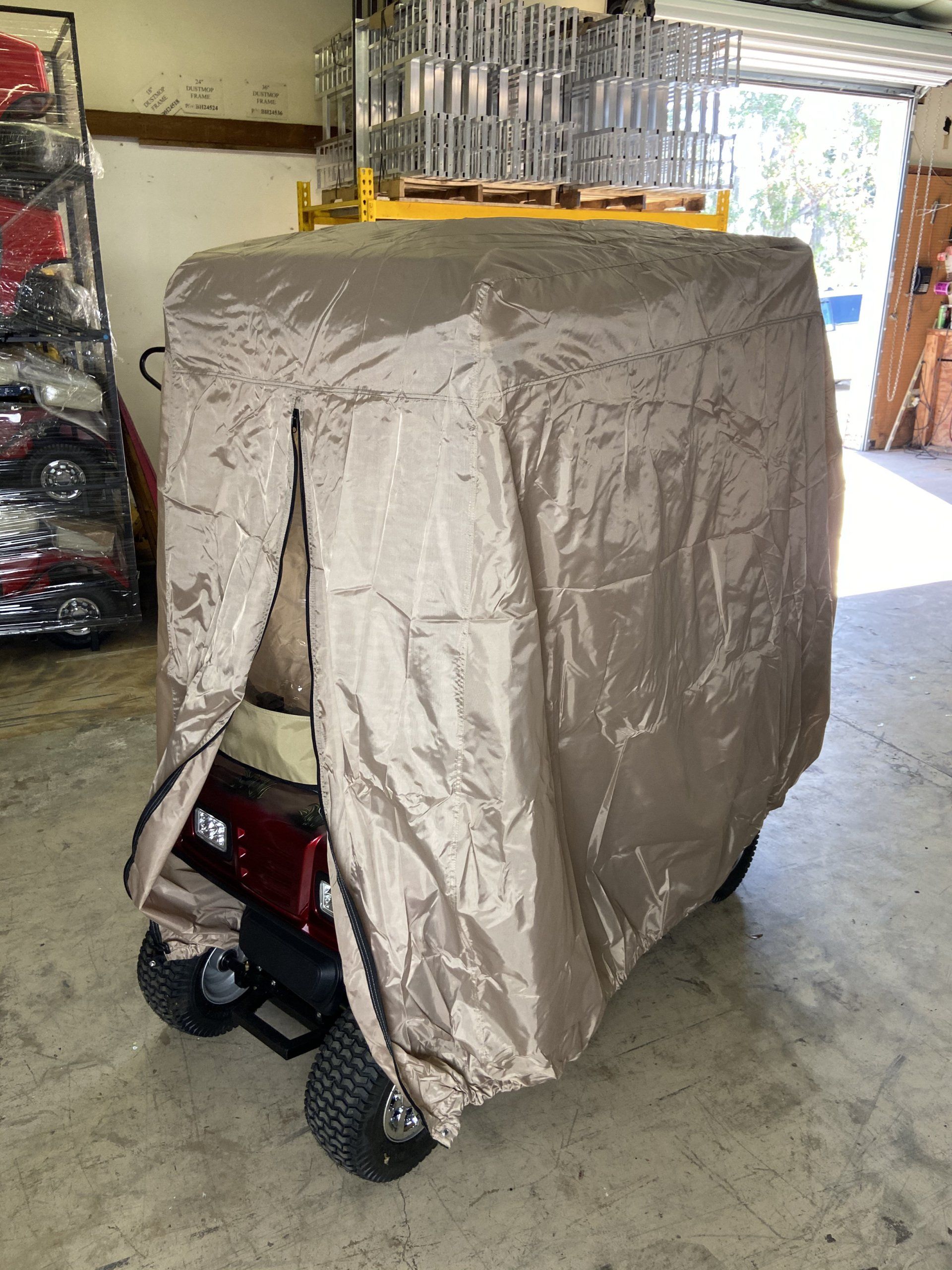 A golf cart with a cover on it is sitting in a garage.