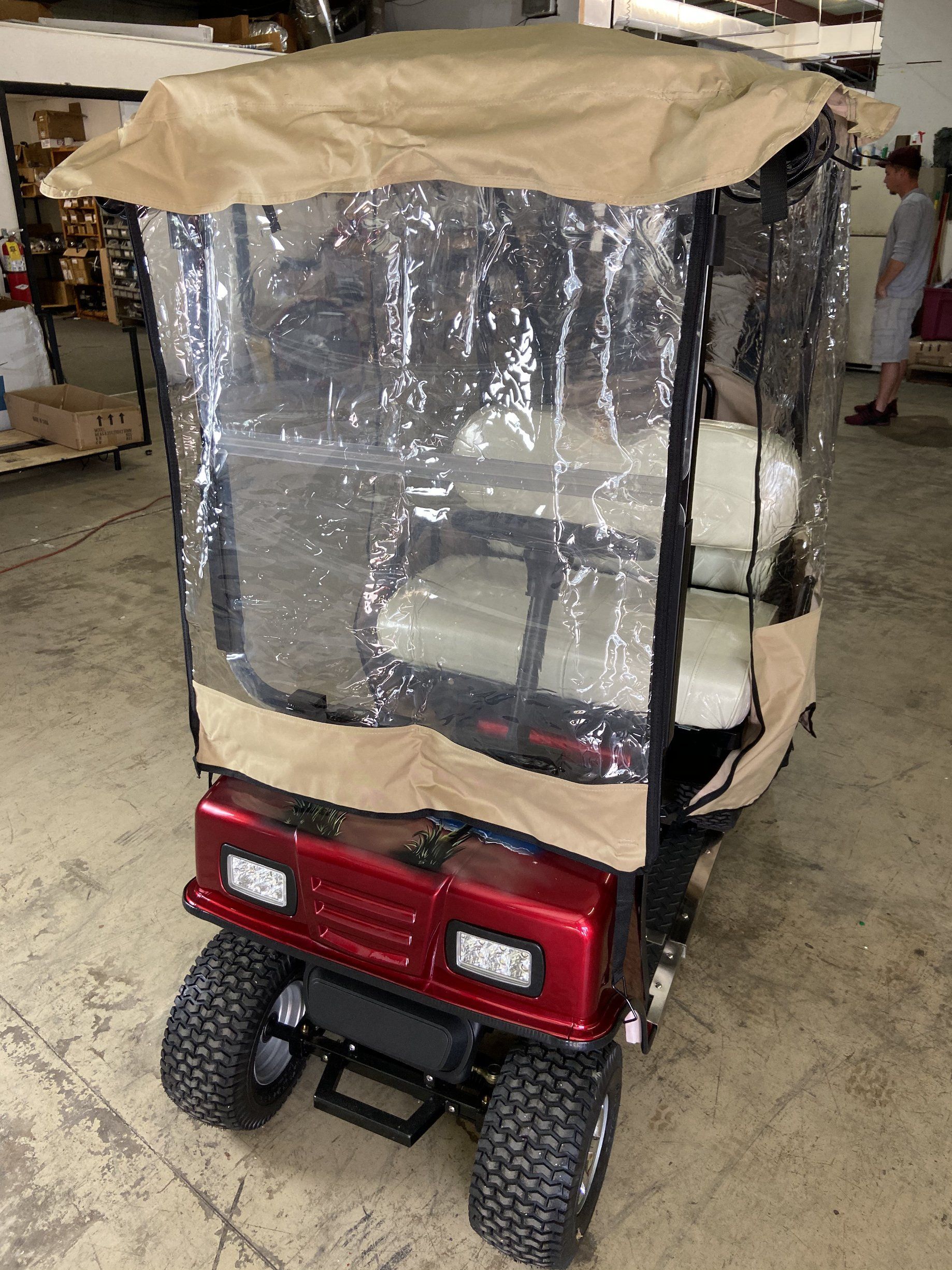 A red golf cart with a clear cover on top of it.