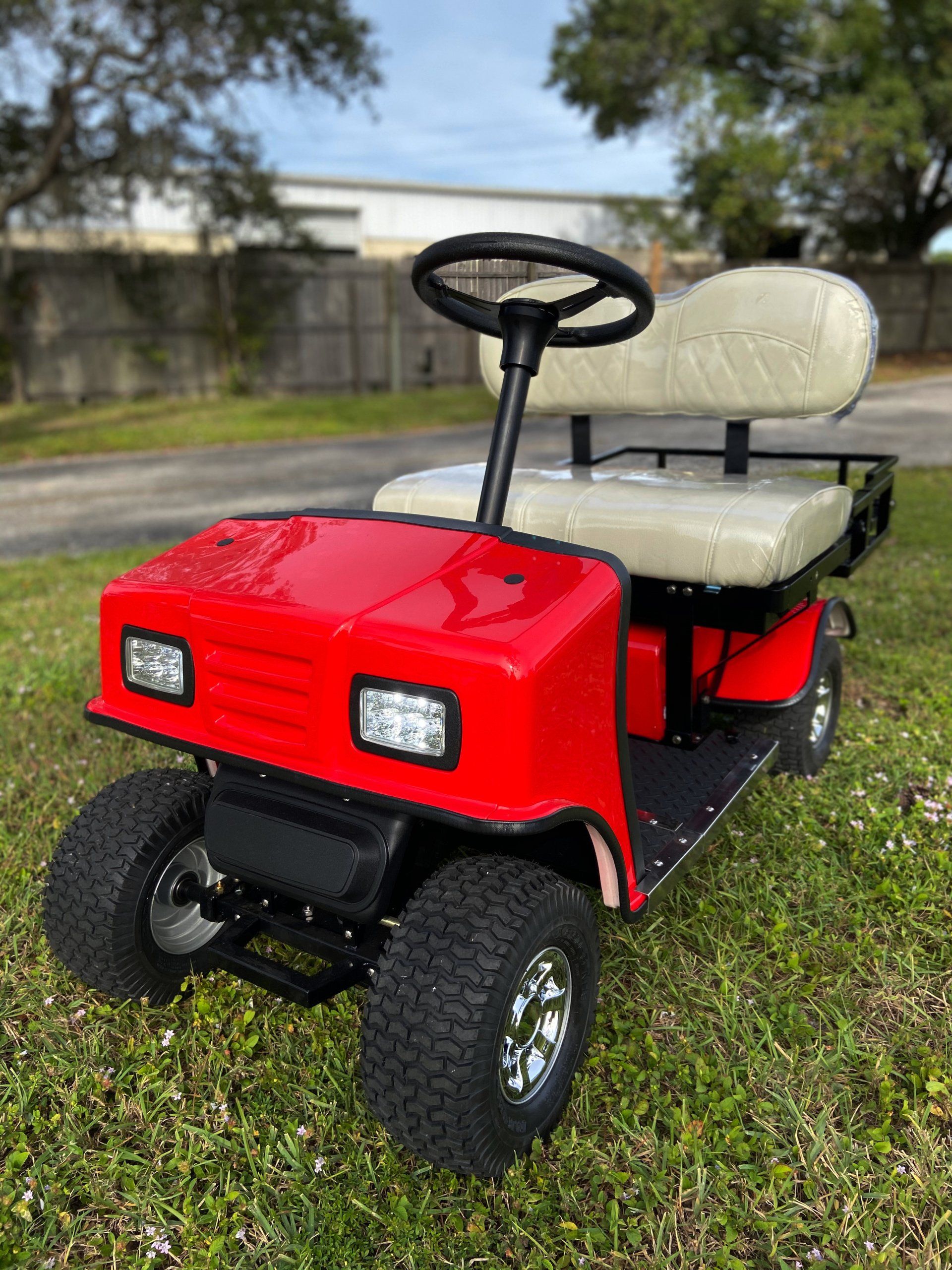 A red golf cart is parked in the grass.