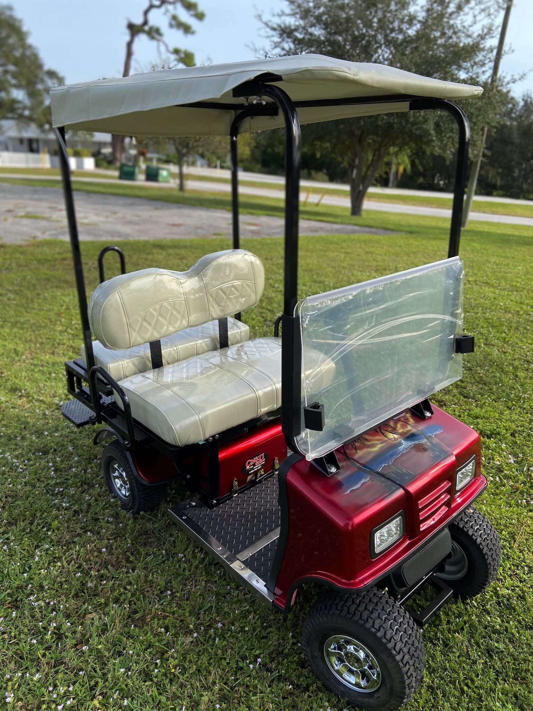 A red golf cart with a canopy is parked in the grass.