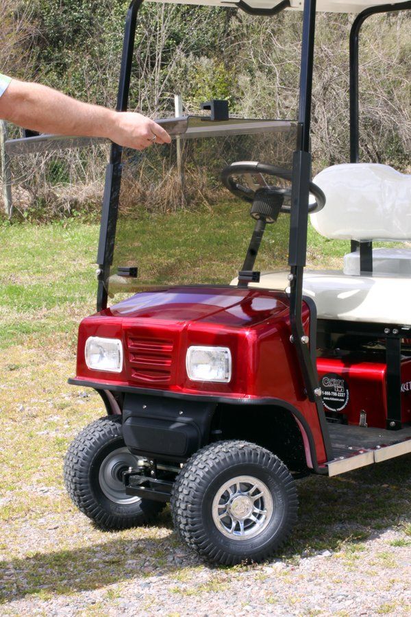 A person is standing next to a red golf cart.