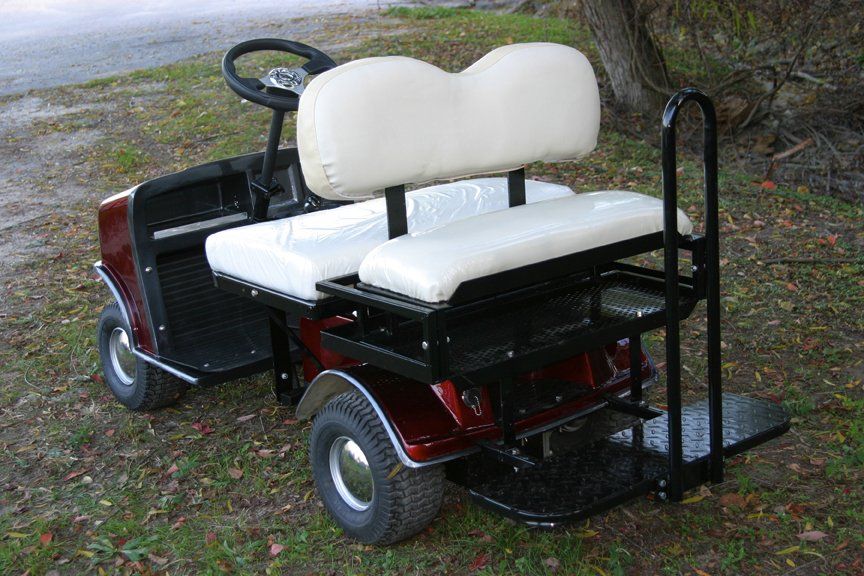 A red golf cart with white seats is parked in the grass