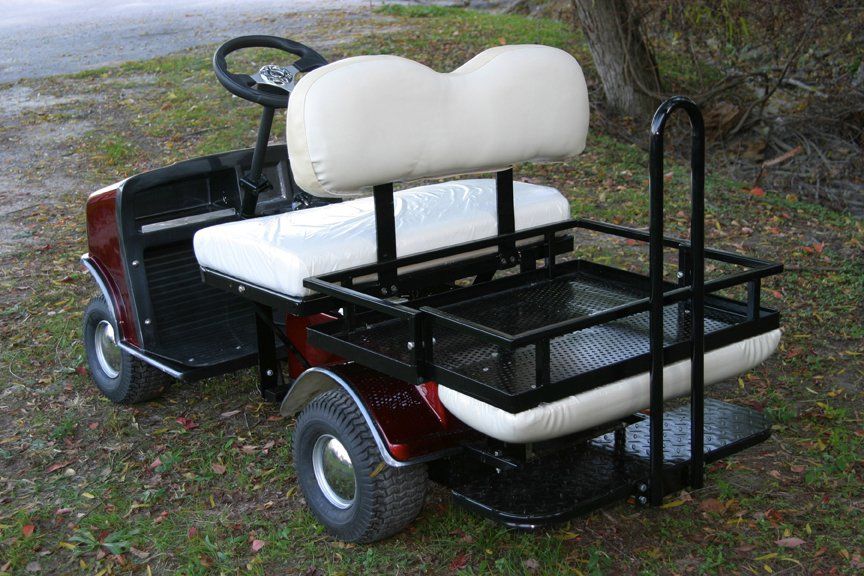 A red and white golf cart is parked in the grass