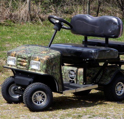 A camouflage golf cart is parked in the grass