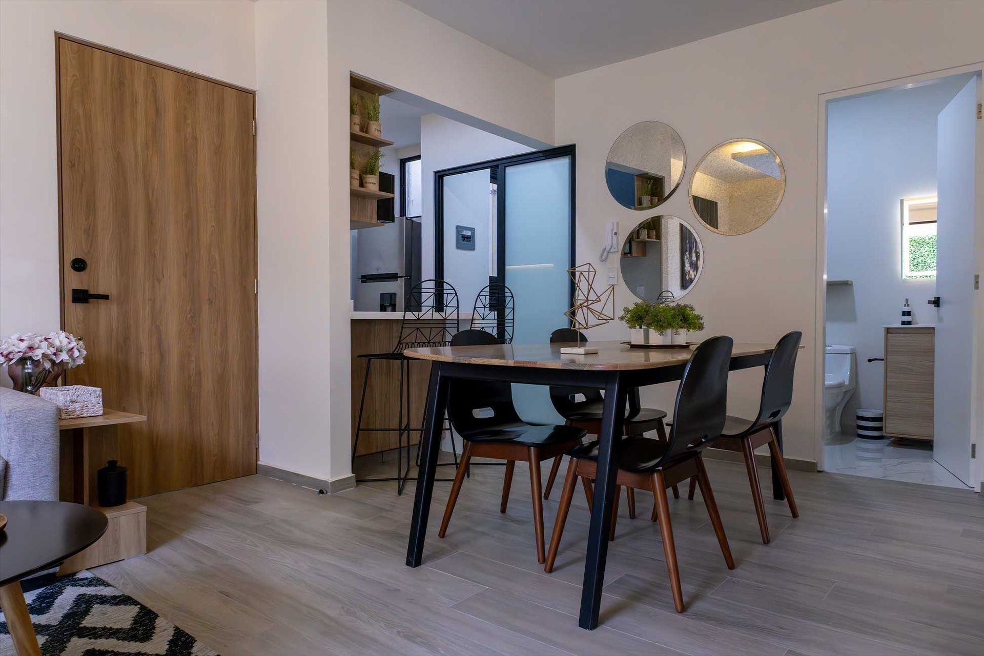 Un comedor con una mesa y sillas y un espejo en la pared.