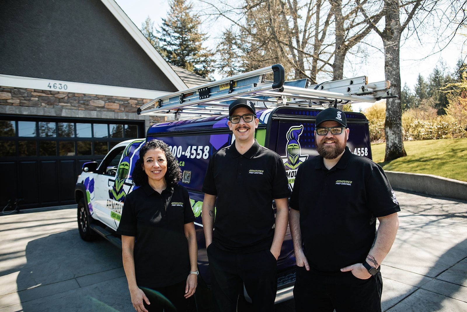 Three people in black shirts standing in front of a purple utility truck and building outdoors