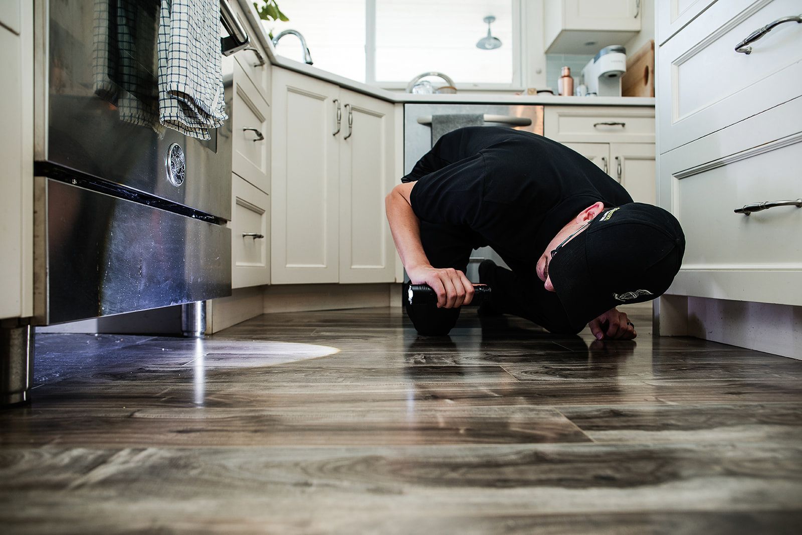 A man is crawling on the floor of a kitchen.