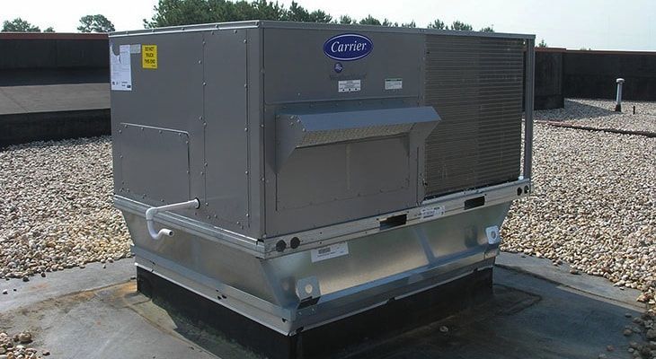 A row of air conditioners are sitting on top of a roof.