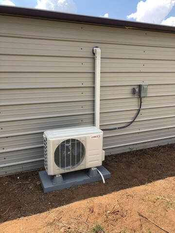 An outdoor air conditioning unit on a concrete pad attached to a metal building.