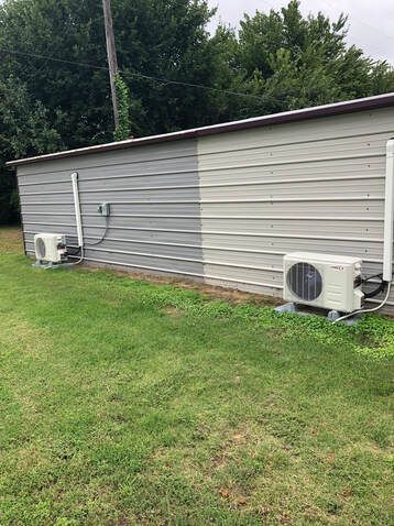 Two air conditioners are sitting on the side of a building.