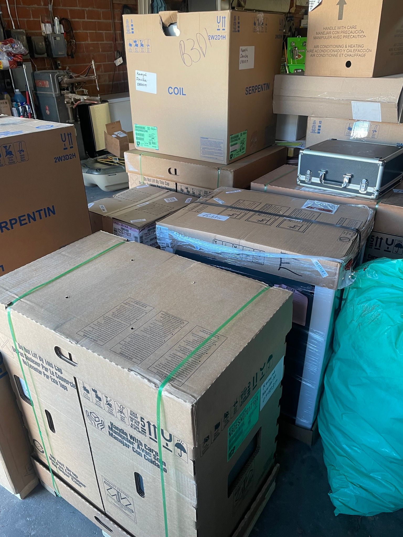 Cardboard boxes stacked, some with labels and green straps, in a storage area.