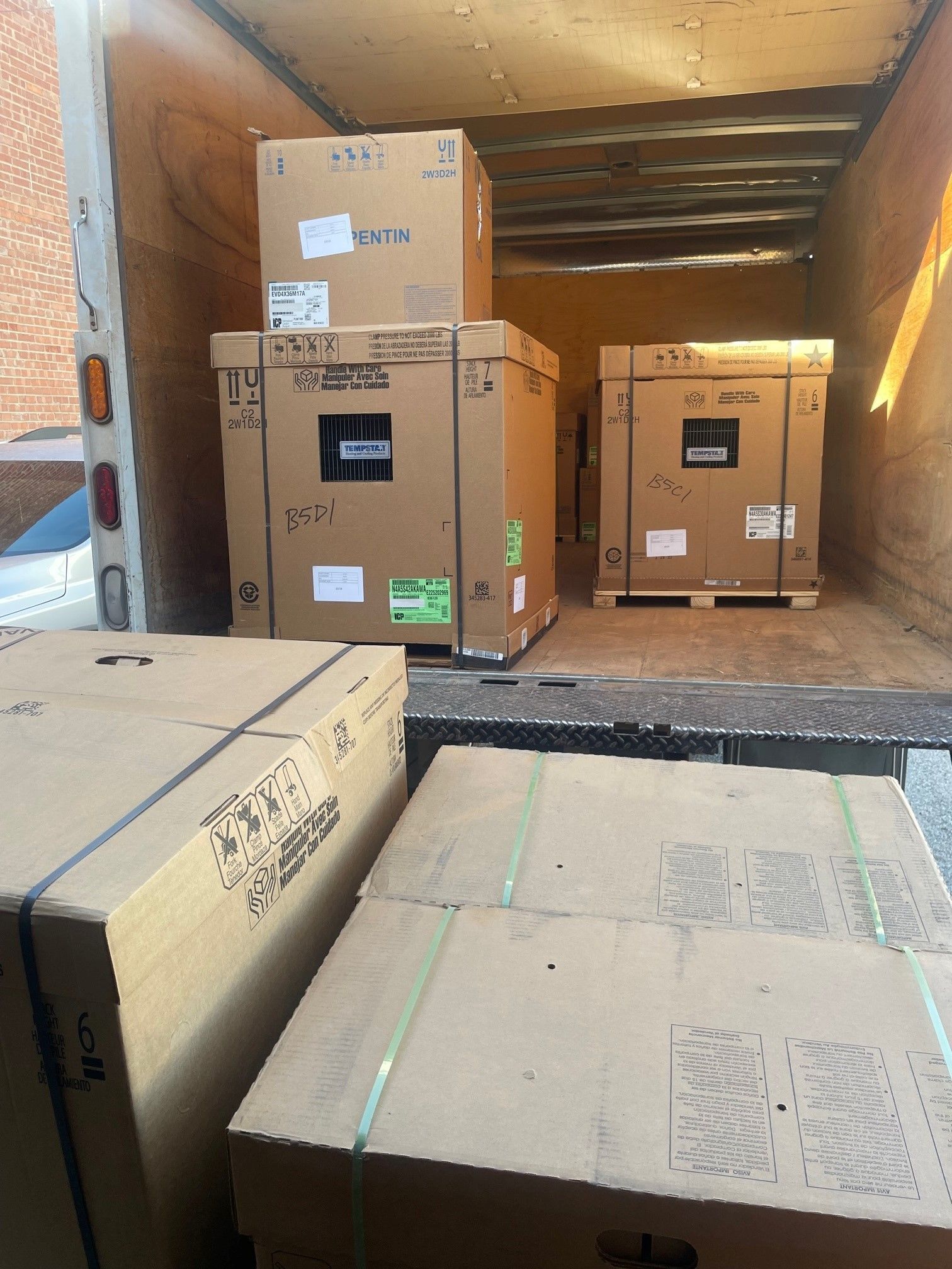 Boxes inside a truck, ready for delivery. Brown cardboard boxes are stacked high.