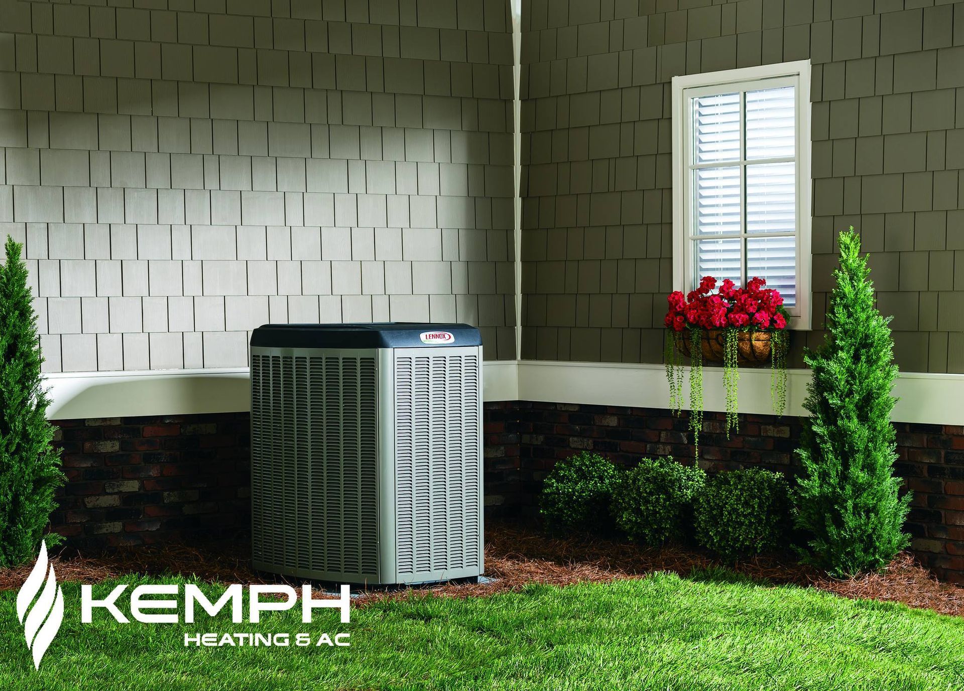 An air conditioning unit in a grassy yard. A window and greenery are in the background.
