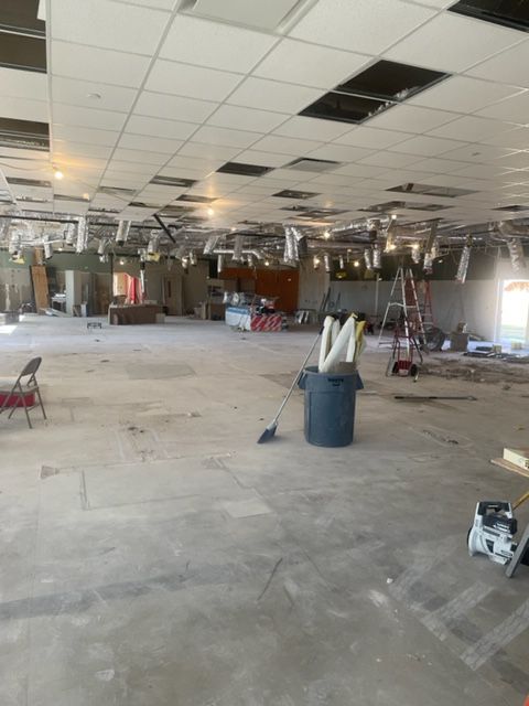 Interior of a commercial space under construction; exposed ceiling, debris, concrete floor.