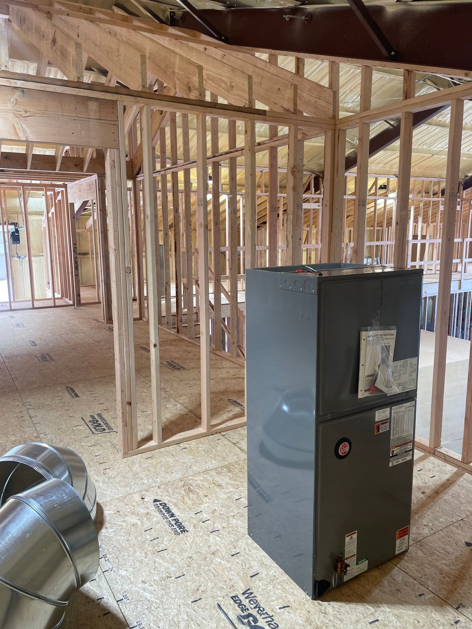 Interior view of a construction site with wooden framing and an HVAC unit.